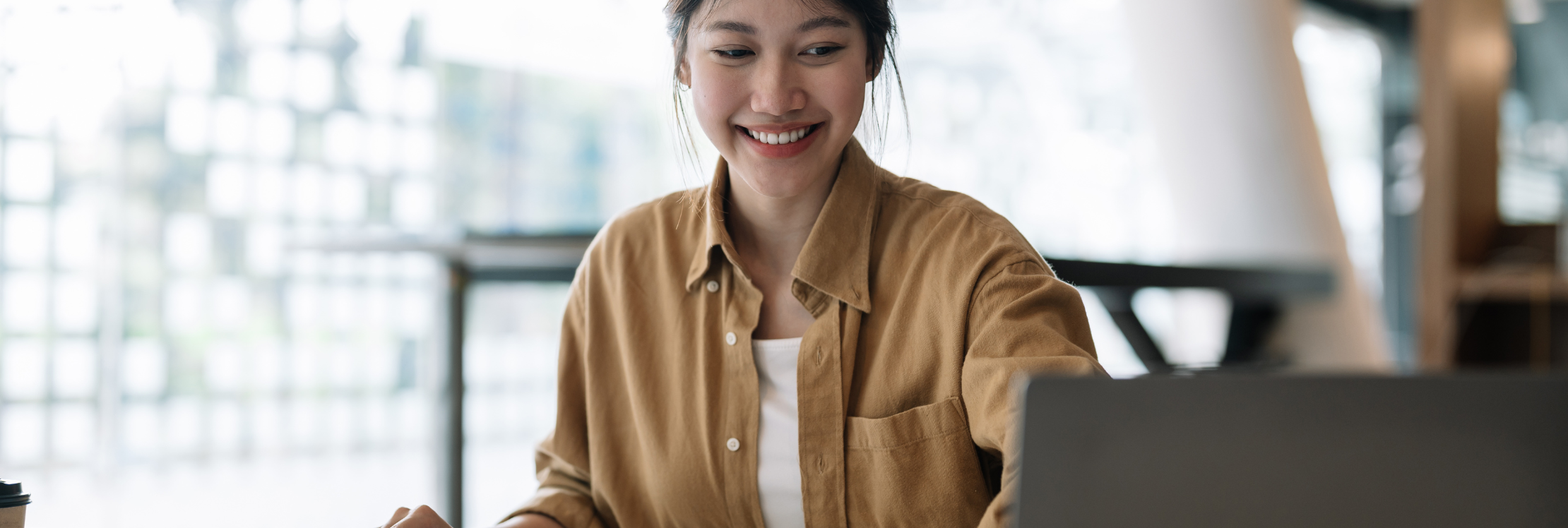 A young woman smiling at a computer screen