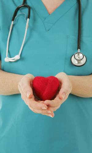 A nurse holding a knitted heart toy