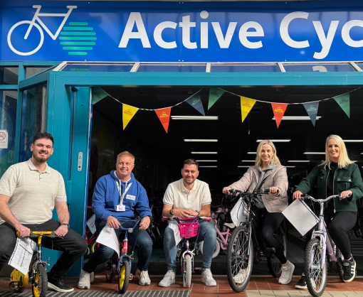 Spencer Clarke Group employees, including Debbie Holden, sat on kids bikes next to Active Cycles