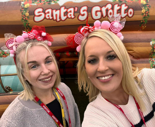 Employees, Debbie Holden and Ellie Wallbank, at a school playground in front of a Santa's grotto
