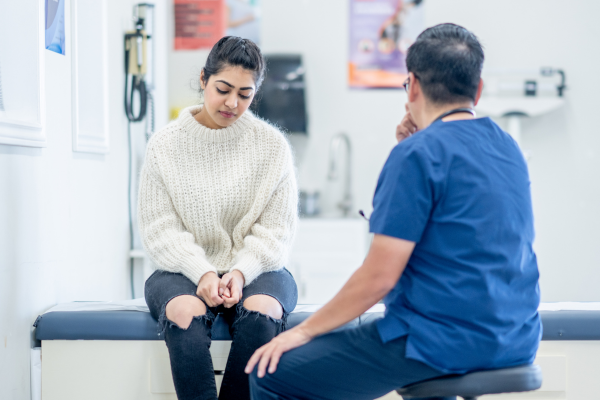 A nurse speaking with a sad looking patient