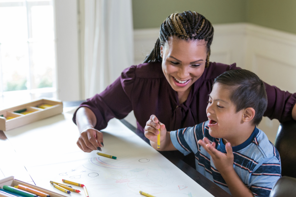 A female sat colouring with a young child