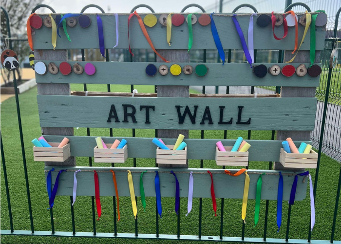 An art wall made out of wooden pallets. The art wall contains chalks.