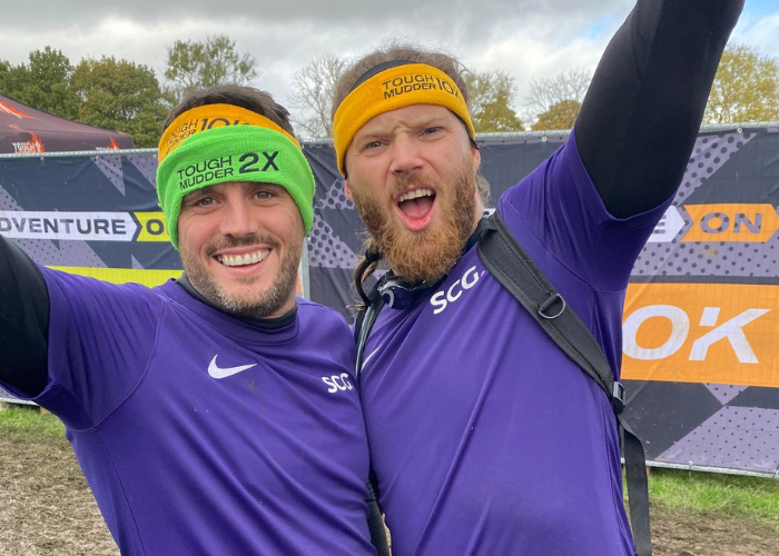 Two male Spencer Clarke Group employees celebrating after completing Tough Mudder