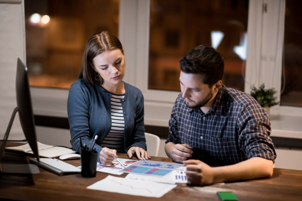 A man and a lady looking at pieces of paper with graphs on them