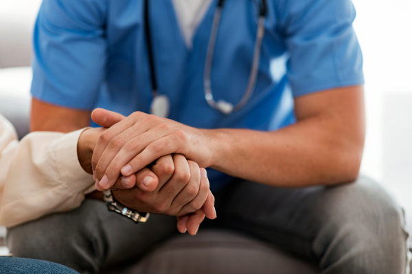 A male nursing professional holding the hand of a patient