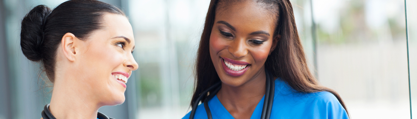 Two female nursing professionals smiling at each other