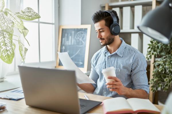 A man working at a laptop wearing headphones