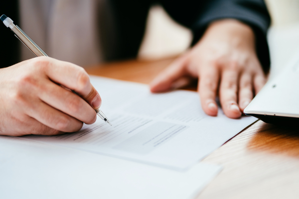 A hand holding a pen above a piece of paper