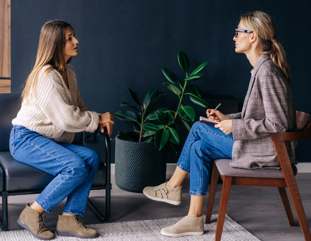 A female professional wearing glasses talking to another lady