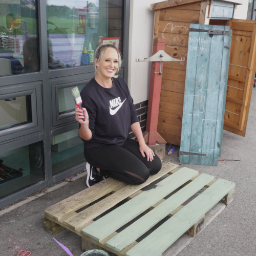 Spencer Clarke Group employee, Debbie Holden, smiling while holding a paint brush. 