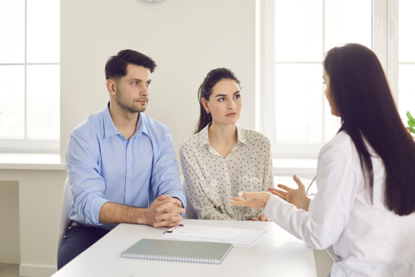 A female professional sat opposite a male and female talking to them