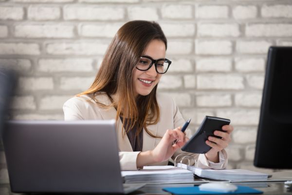 A lady sat at a desk looking at a calculator