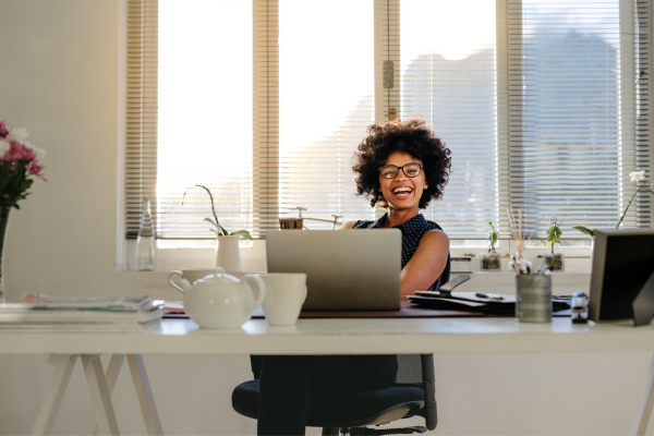 A lady wearing glasses sat at a desk smiling