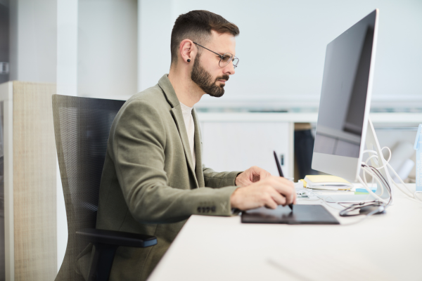 A man sat at a desk looking at a computer screen