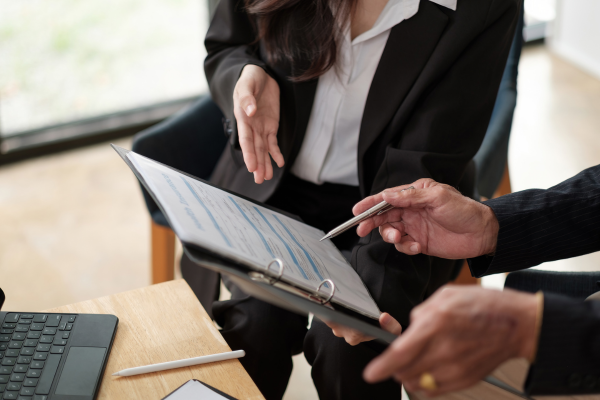 A pair of hands holding a clipboard showing somebody else the paper on it