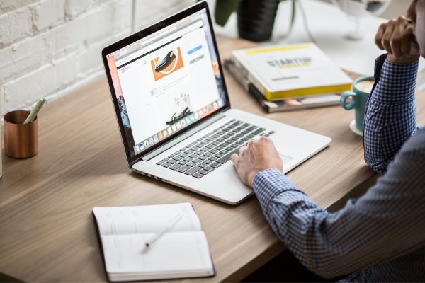 An open laptop on a desk with a hand resting on it