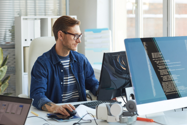 A man wearing glasses and a stripy top looking at a computer screen