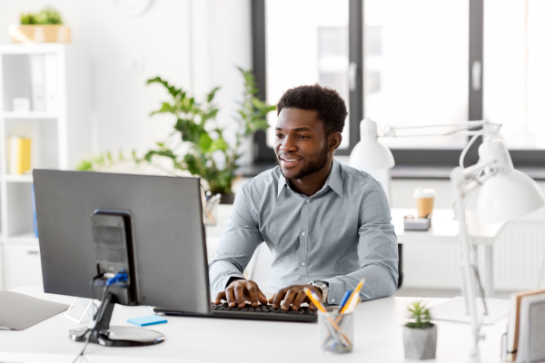 A man wearing a grey shirt sat at a desk using a computer