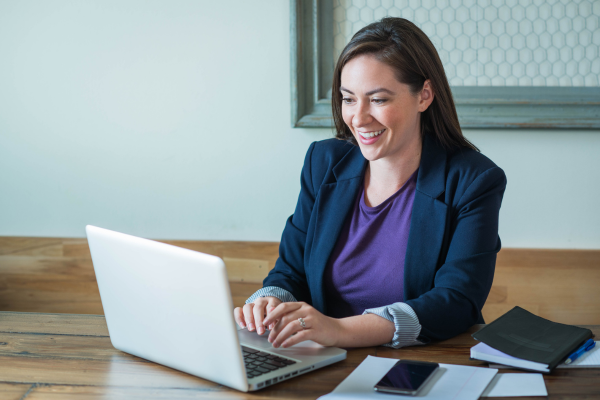 A lady wearing a purple top and black blazer looking at a laptop screen