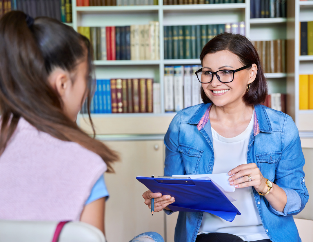 A female professional wearing glasses smiling at a young woman