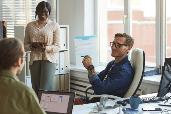 Two men and a woman in an office smiling and having a conversation