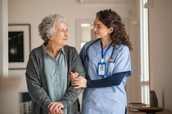 A female nursing professional linking arms with an elderly female patient