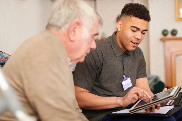 A male support worker showing a man an electrical device