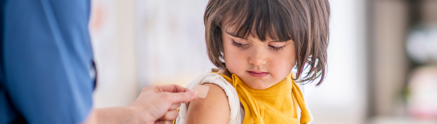 A healthcare professional applying a plaster to a young girl's arm