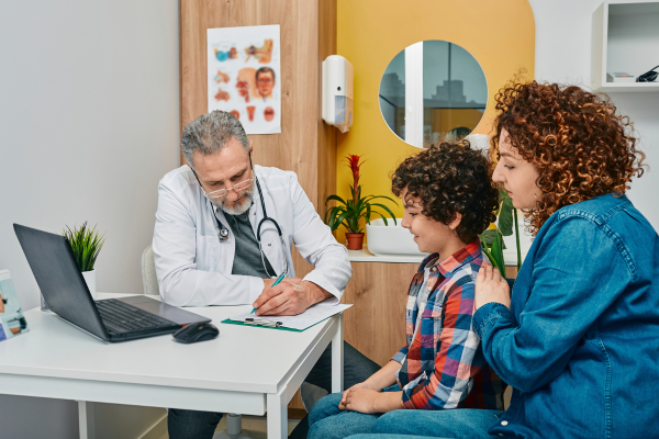 A male Paediatrician speaking to a young boy and a female adult