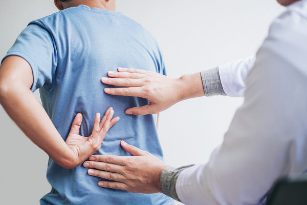 A healthcare professional touching the back of a patient