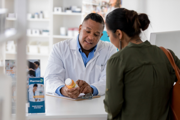 A male Pharmacist helping a lady at a shop counter