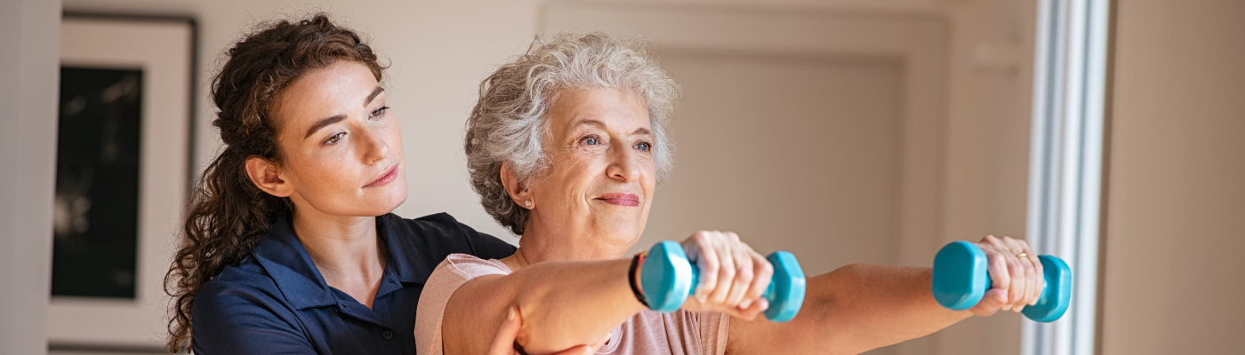 A female physiotherapist helping a female patient who is holding weights