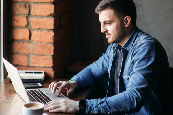 A man in a blue shirt working at his laptop