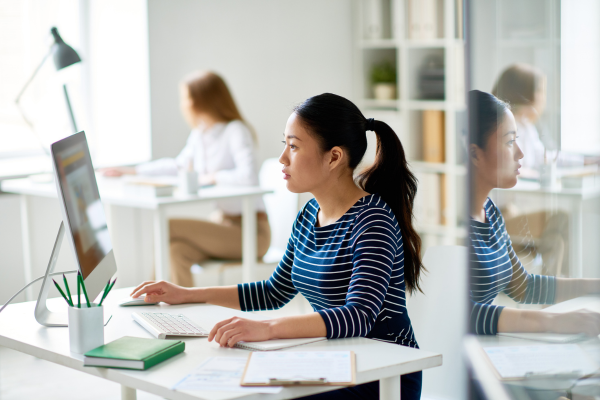 A lady sat at a desk looking at a computer screen