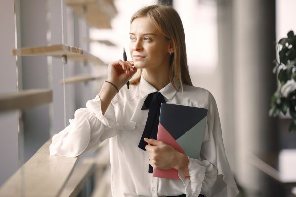 A lady holding a notebook looking out of a window