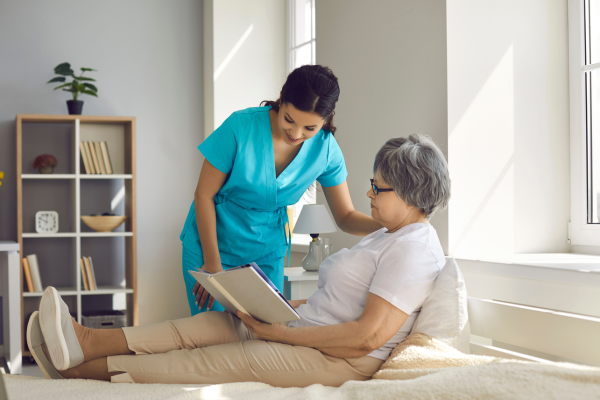 A female residential support worker looking in a book with an elderly lady