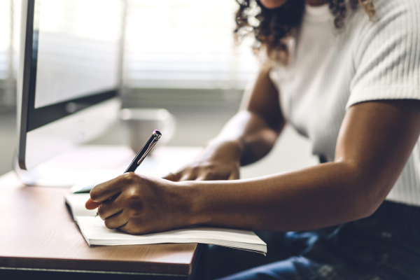 A lady sat at a desk writing on paper