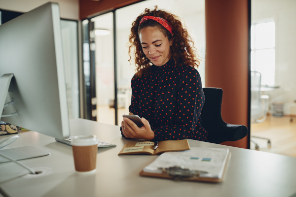 A lady sat at her desk looking at her phone