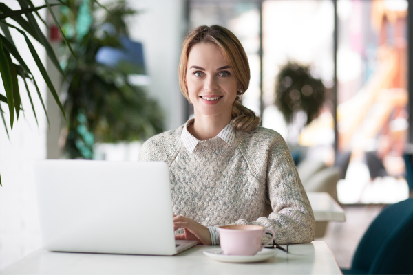 A lady wearing a knitted cream jumper with an open laptop in front of her