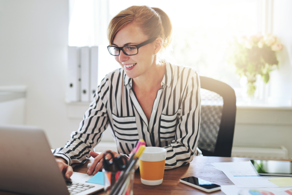 A lady sat at a desk working on a laptop