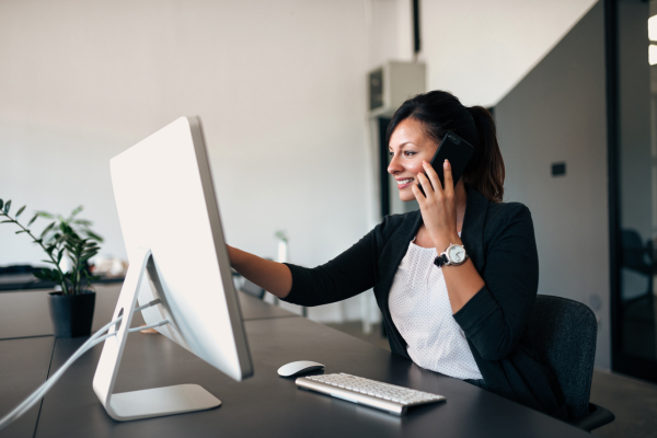 A lady looking at a computer screen whilst on the phone