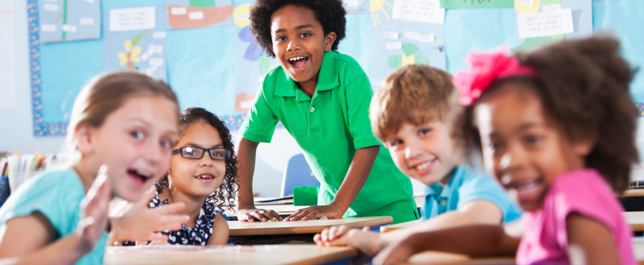 Five young children sat around a desk smiling