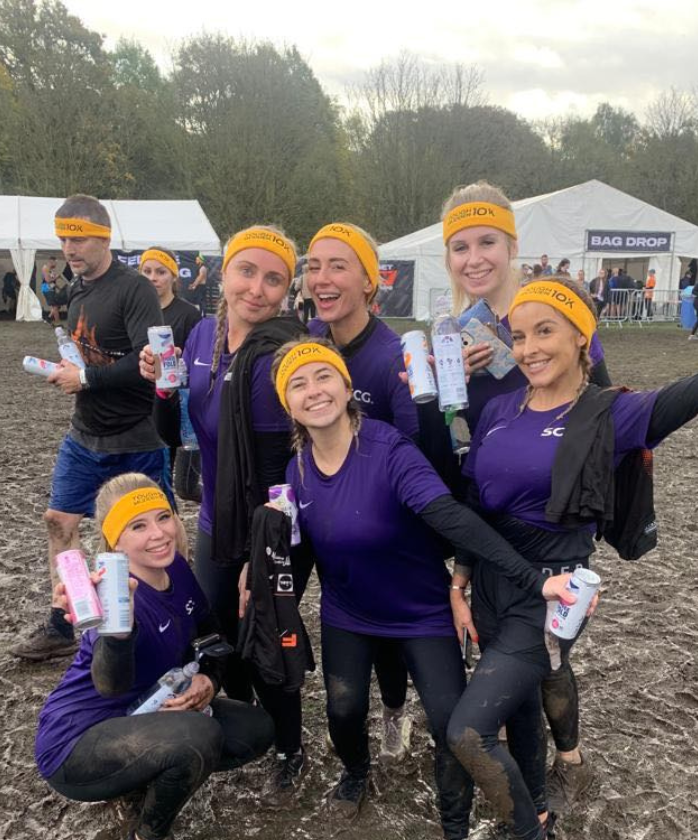 Six female Spencer Clarke Group employees celebrating at Tough Mudder