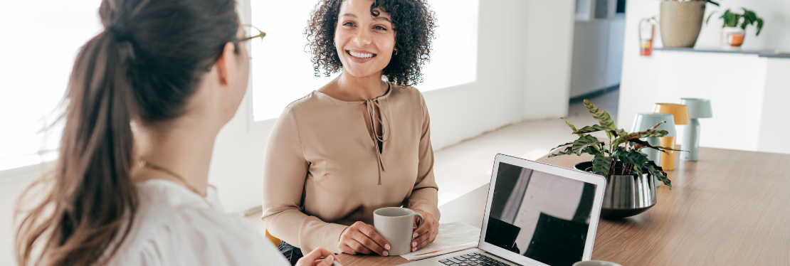 Two women sat by a laptop