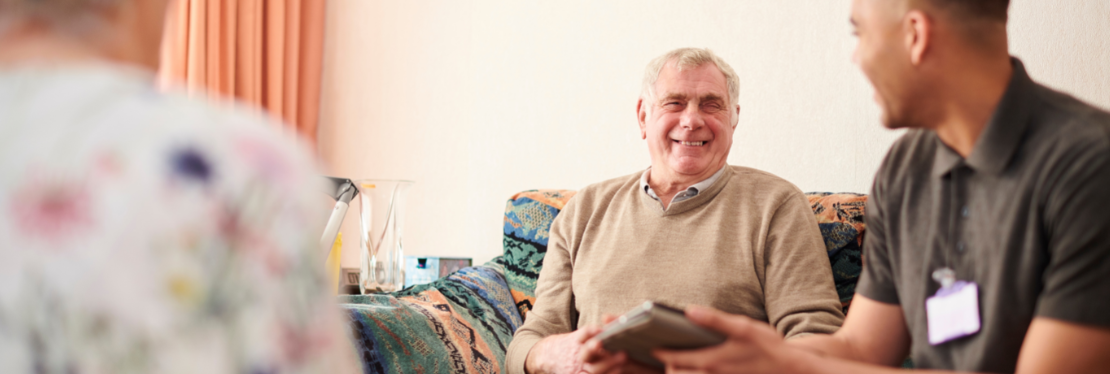 A care provider smiling at an elderly man