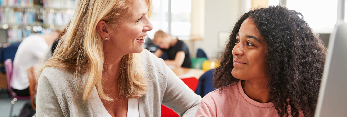 A teacher smiling at a teenager 