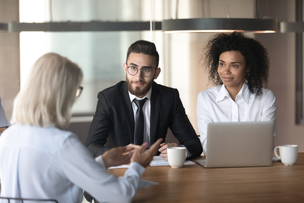 A lady sat opposite a man wearing a suit and another lady at a desk