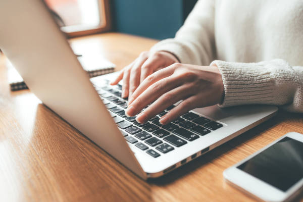 Hands typing on a laptop keyboard