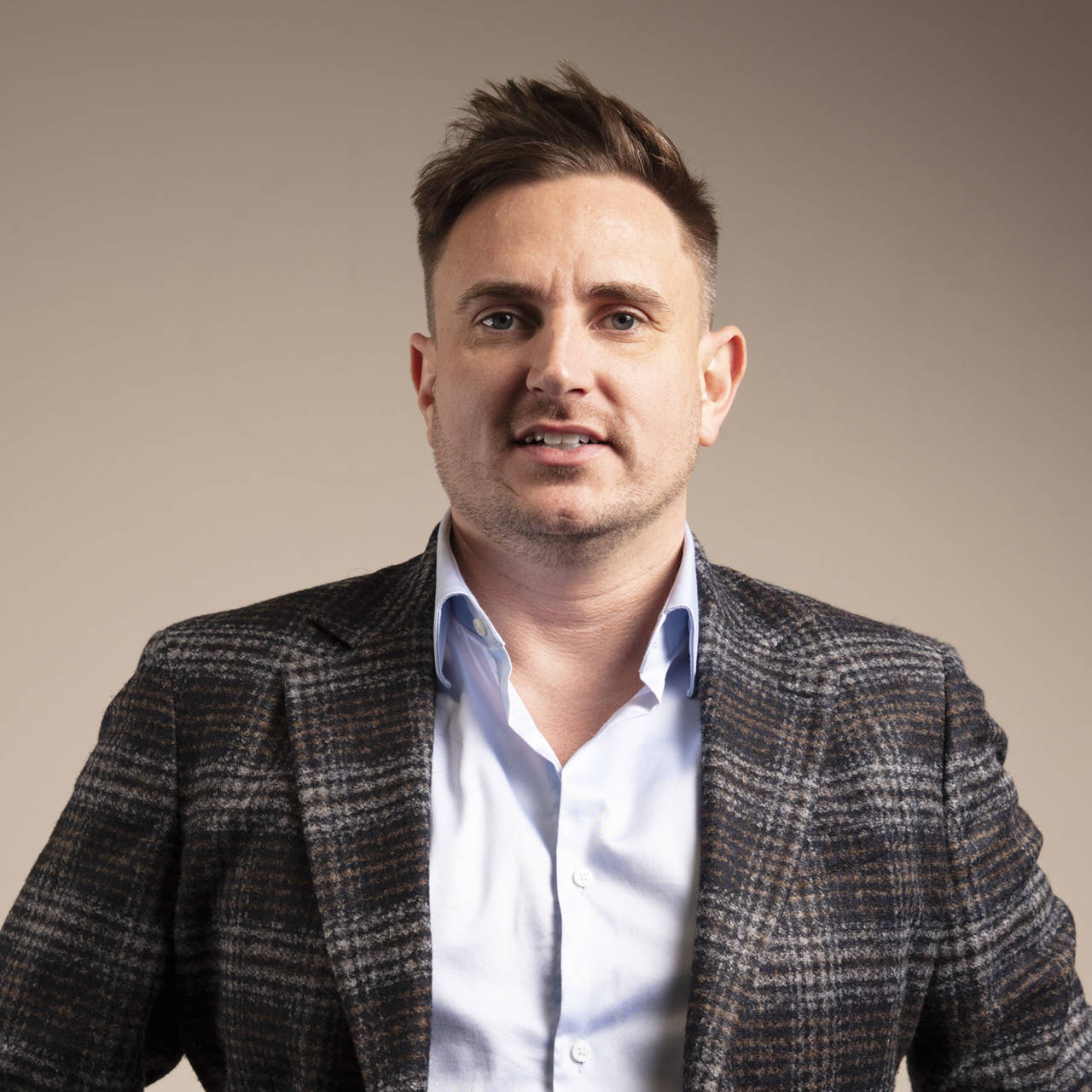 A man in a dress-shirt and checked blazer 